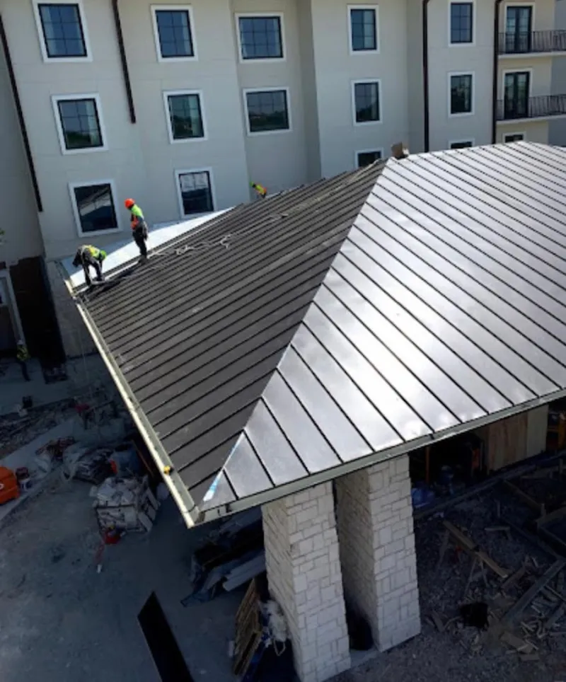 Crew installing standing seam metal roof panels on a commercial project in Zachary